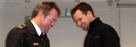 Pascal Remarque wird zum Oberbrandmeister befördert, Herr Hartl übergibt die Beförderungsurkunde und die Dienstgradabzeichen.